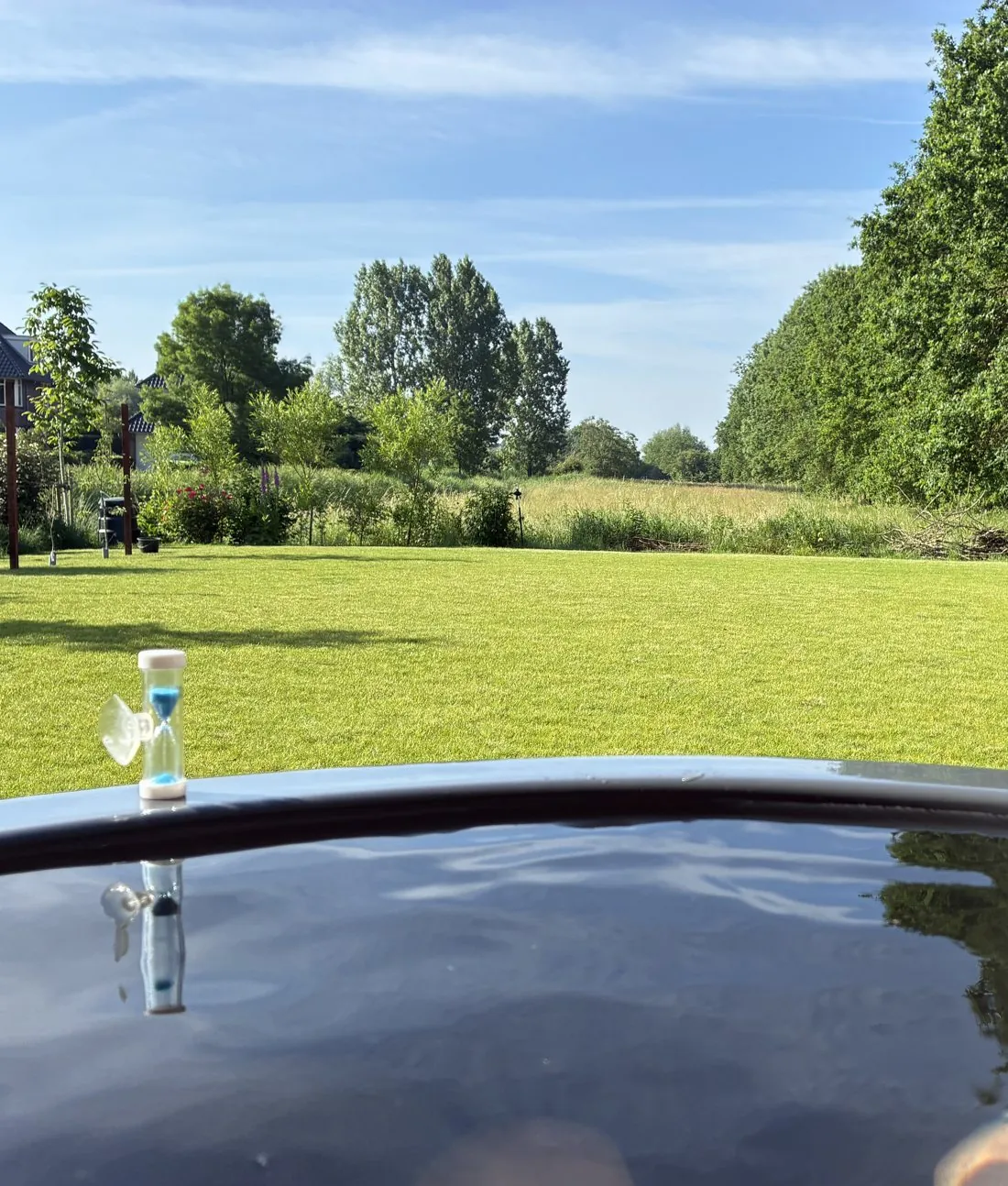 Uitzicht over de wei vanuit het ijsbad, met zandloper op de rand